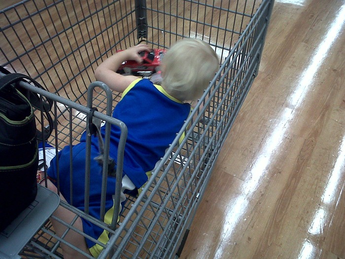laying down in the cart playing with his truck