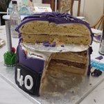 Half eaten cake of Purple Minion.  Bottom later is a walnut gateaux, top layer Victoria Sponge